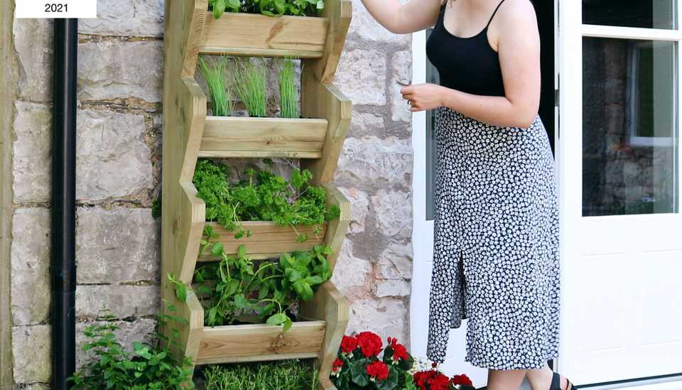 Lady picking herbs from Zest's Tall Vertical Herb Stand